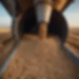 A detailed view of a used grain bin unloading auger in a field setting